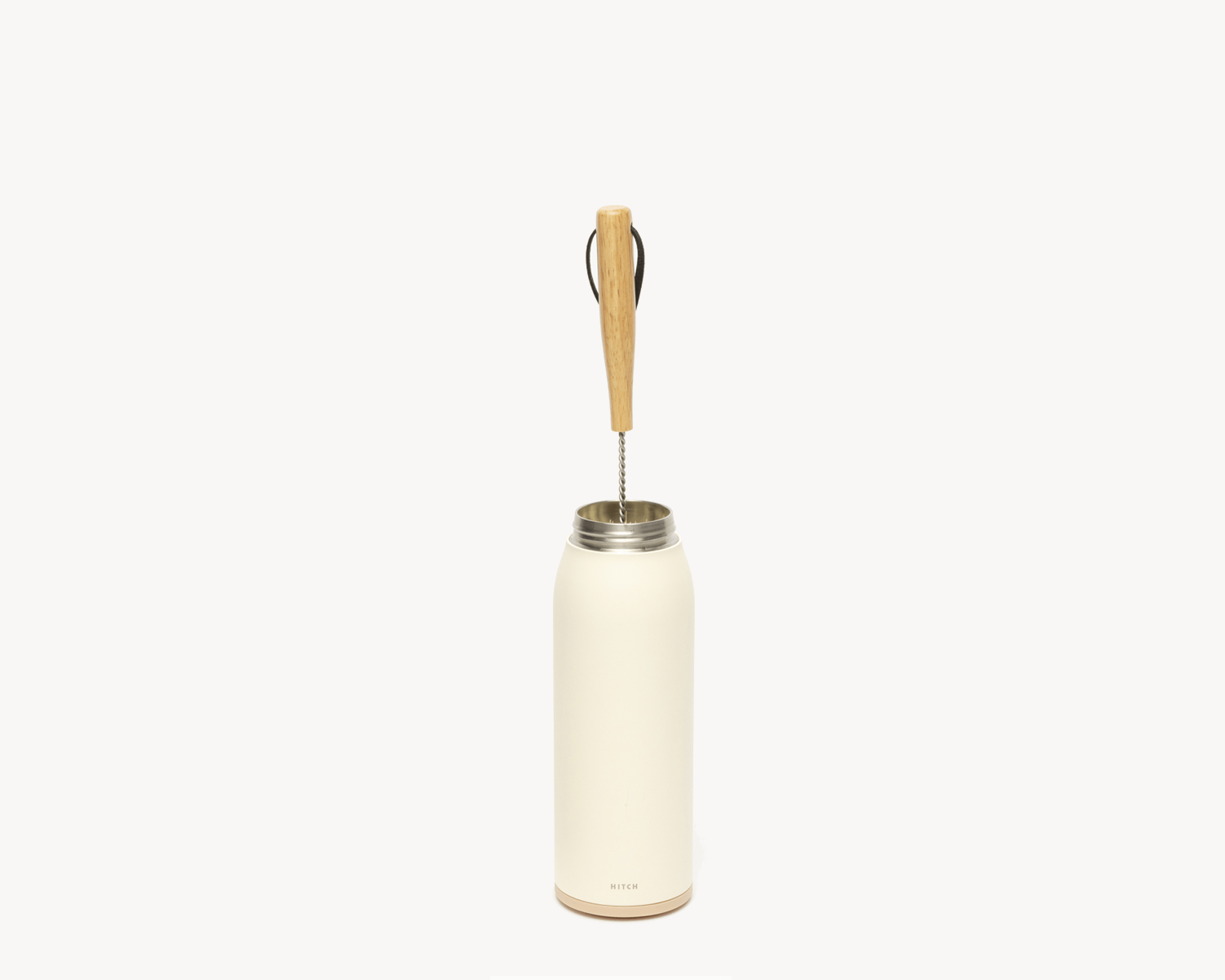 Hitch Bottle Brush with Natural Sisal Fibers, a stainless steel rod, and wooden handle inside Hitch Bottle and Cup in Natural White