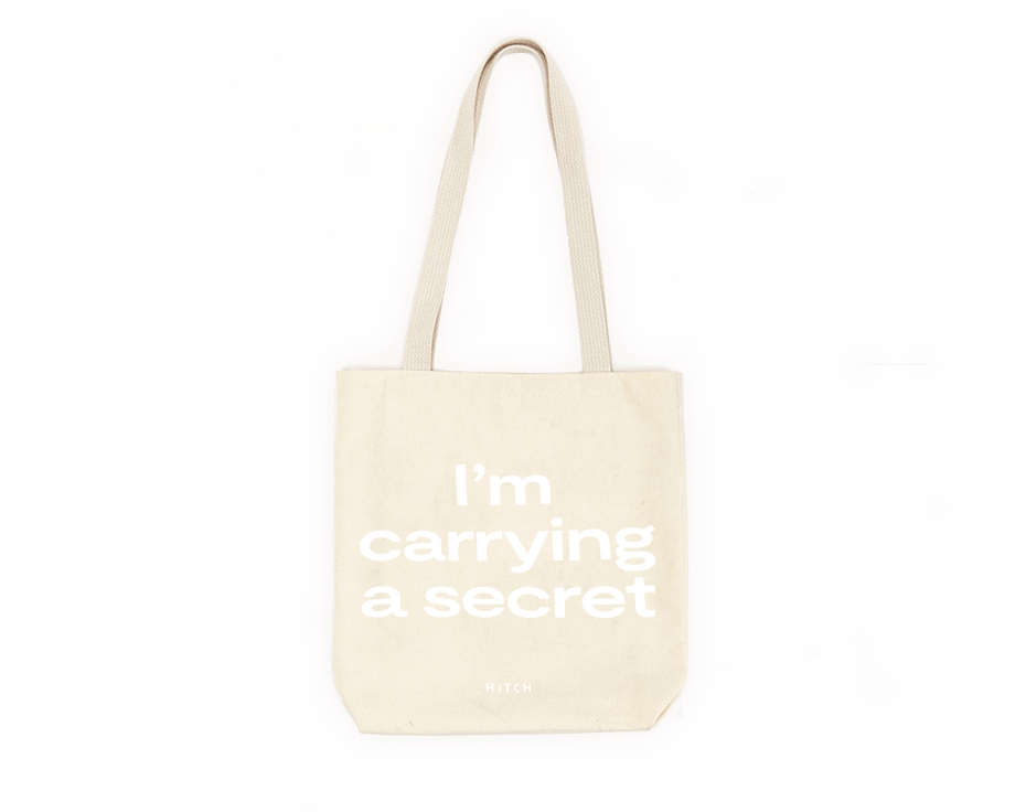 Canvas Tote with shoulder strap, text says "I'm Carrying a Secret" in white font