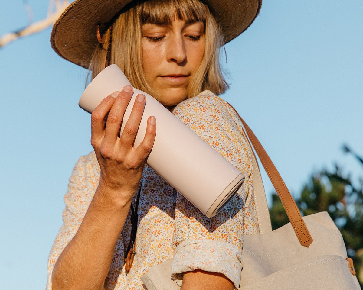 Woman placing Hitch Bottle and Cup in Pale Blush into her bag 