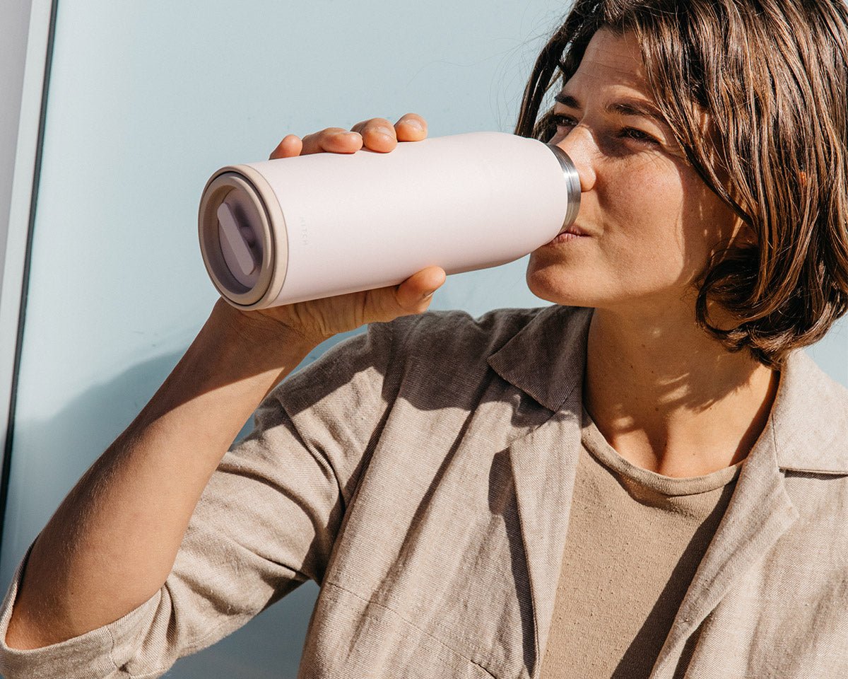 Woman drinking water from the Hitch Bottle and Cup in Pale Blush
