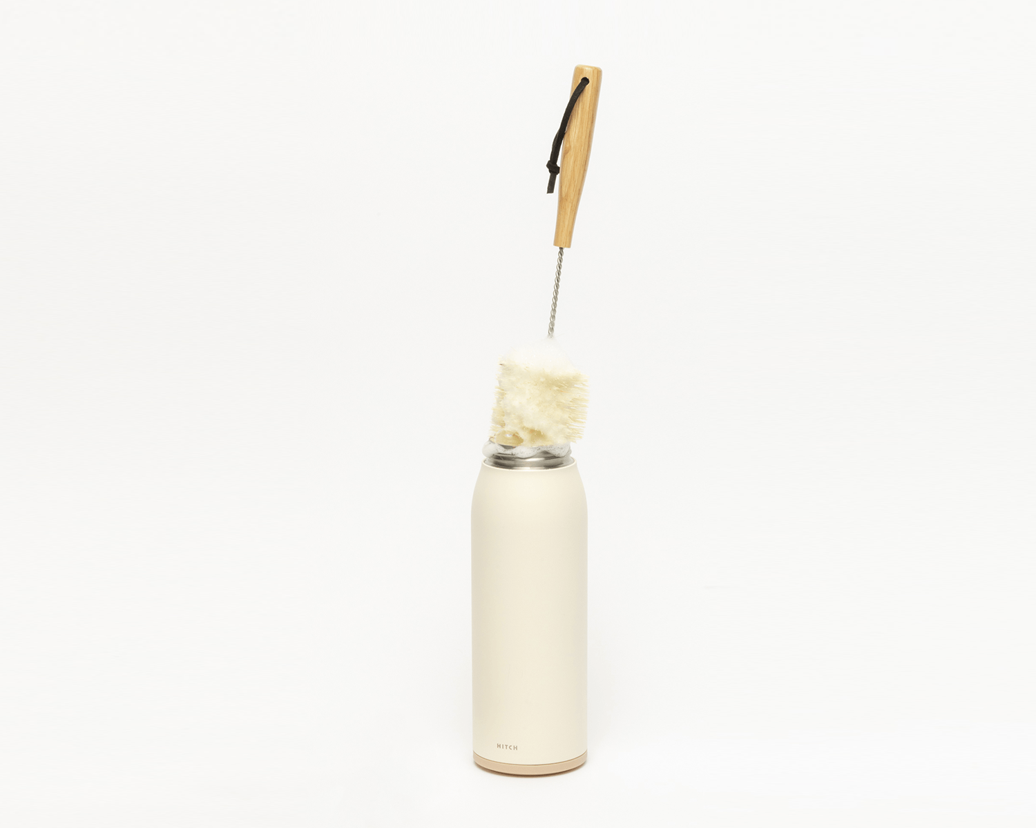 Hitch Bottle Brush with Natural Sisal Fibers, a stainless steel rod, and wooden handle cleaning the Hitch Bottle and Cup in Natural White